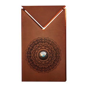 Peut inclure: Une sculpture murale en métal rouillé avec un motif géométrique et un miroir rond au centre. Le miroir reflète le ciel et les nuages.