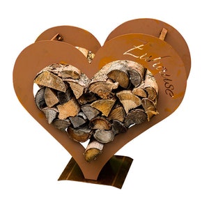 May include: A heart-shaped metal log rack with the word "Zuhause" inscribed on the side. The rack is filled with stacked firewood.