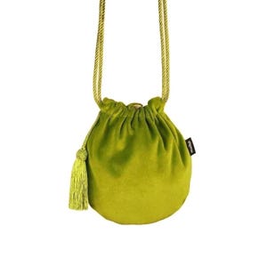 May include: A lime green velvet drawstring bag with a matching tassel and shoulder strap. The bag has a round shape and a small black tag with white text.