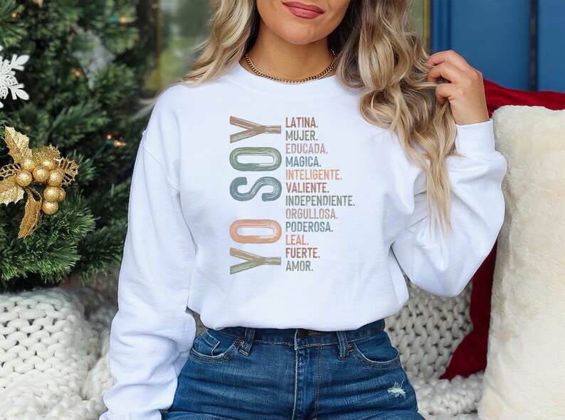 May include: White sweatshirt with the text "YO SOY" in colorful letters and a list of Spanish words describing a Latina woman. The words are in a vertical column and include "Latina, Mujer, Educada, Magica, Inteligente, Valiente, Independiente, Orgullosa, Poderosa, Leal, Fuerte, Amor."