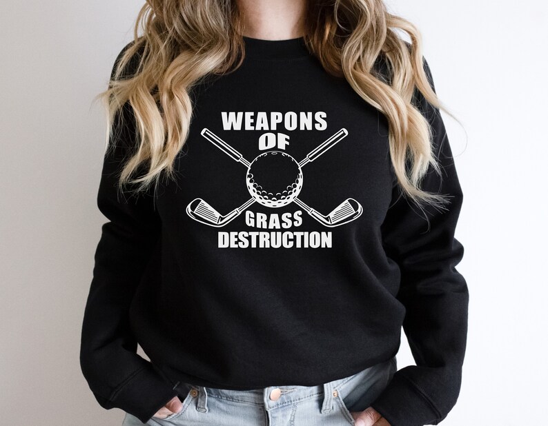 May include: Black sweatshirt with white text that reads "Weapons of Grass Destruction" and a graphic of a golf ball with two crossed golf clubs.