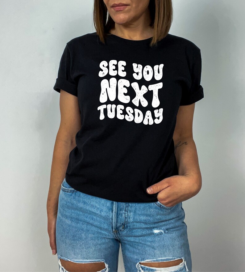 May include: A black t-shirt with white text that reads "See You Next Tuesday" in a retro font.
