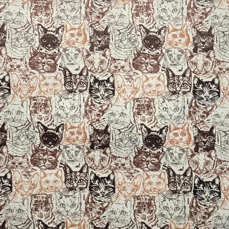 May include: A fabric pattern featuring a dense, repeating illustration of cat faces in shades of brown, tan, and dark charcoal on a light cream background. The design displays various feline expressions and ear shapes in a continuous print.