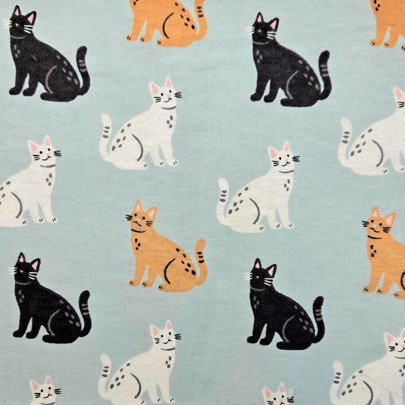 May include: A light blue fabric featuring a repeating pattern of illustrated cats in black, white, and orange. Each cat is depicted in a seated position with visible whiskers, ears, and tails, arranged in a grid-like layout across the material.