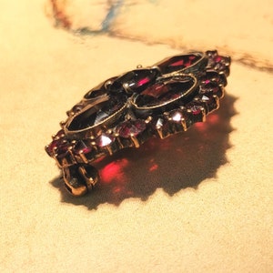 May include: A vintage brooch with a large, ornate design featuring a cluster of dark red garnets set in gold.