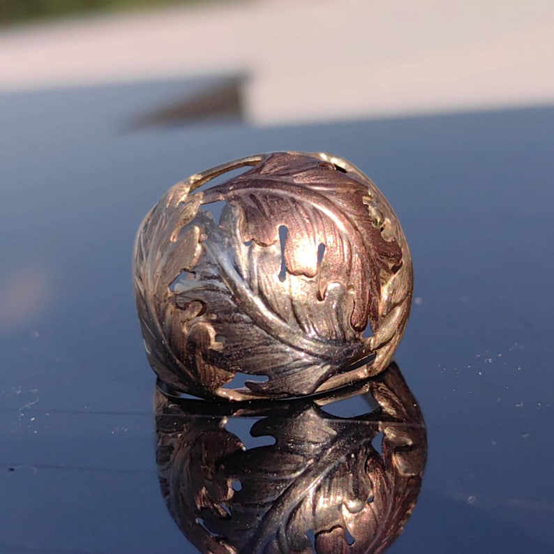 May include: A silver ring with a detailed leaf design. The leaves are cut out and have a two-tone finish, with some leaves appearing gold and others silver.