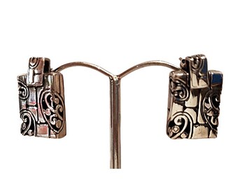 May include: A pair of silver earrings with a geometric design. The earrings are square shaped and have a detailed pattern of swirls and lines.