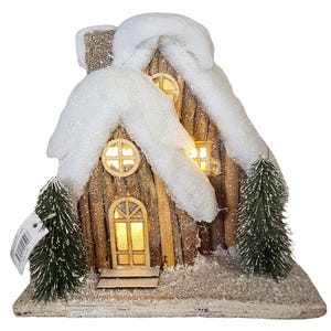 以下が含まれることがあります： 雪の屋根と光る窓のある木製のクリスマスの家。家は模造雪と小さな松の木で飾られています