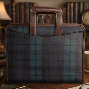 May include: A rectangular briefcase featuring a dark green and black plaid pattern. The bag has a structured brown leather handle and matching brown leather trim along the edges. It includes a front pocket with a curved top seam design.