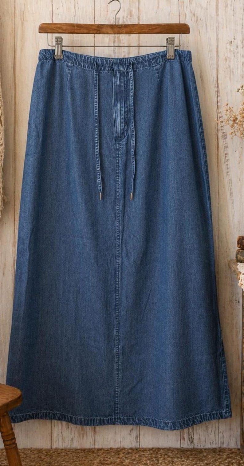 May include: A long, blue denim skirt featuring an elasticated waistband with a drawstring closure. The skirt has a straight, floor-length silhouette with a central vertical seam running down the front and a hemline finished with double stitching.