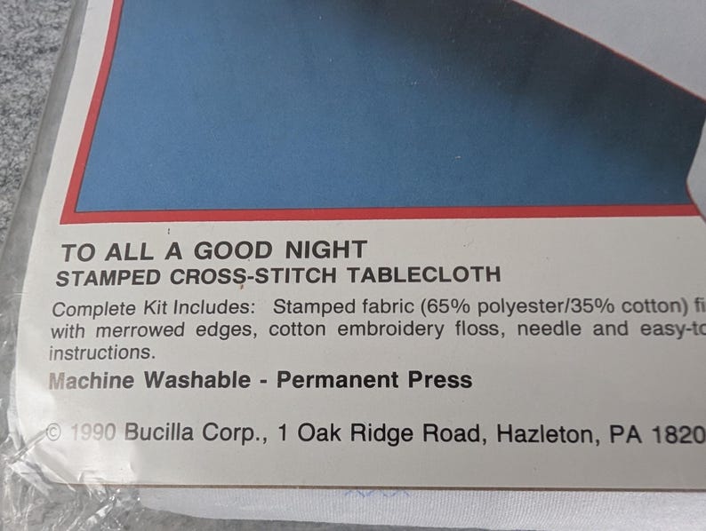 Puede incluir: Paquete para un kit de mantel de punto de cruz estampado. El texto dice "To All A Good Night". El kit incluye tela estampada, hilo de bordar y una aguja. La tela es 65% poli&eacute;ster y 35% algod&oacute;n.
