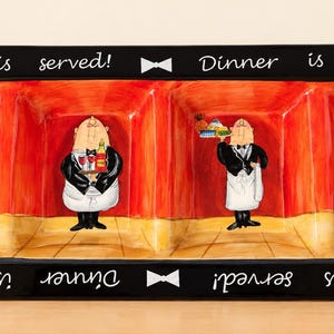 May include: A rectangular ceramic serving tray with four divided sections. The black border features white bow tie icons and the text "Dinner is served!" repeated. Inside, four painted waiters in black and white uniforms stand against a red wall.