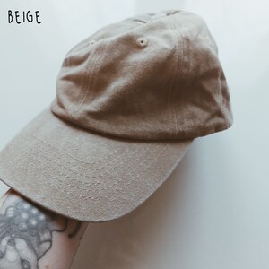 K&ouml;nnte beinhalten: Eine beige Baseballkappe mit einem gebogenen Schirm. Die Kappe ist aus weichem Baumwollstoff.