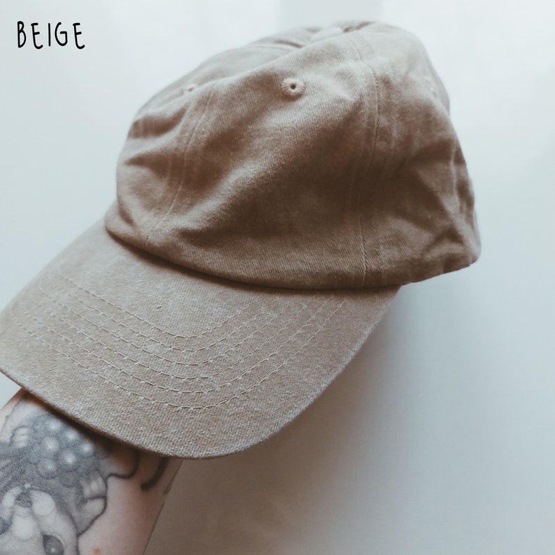 K&ouml;nnte beinhalten: Eine beige Baseballkappe mit einem gebogenen Schirm. Die Kappe ist aus weichem Baumwollstoff.