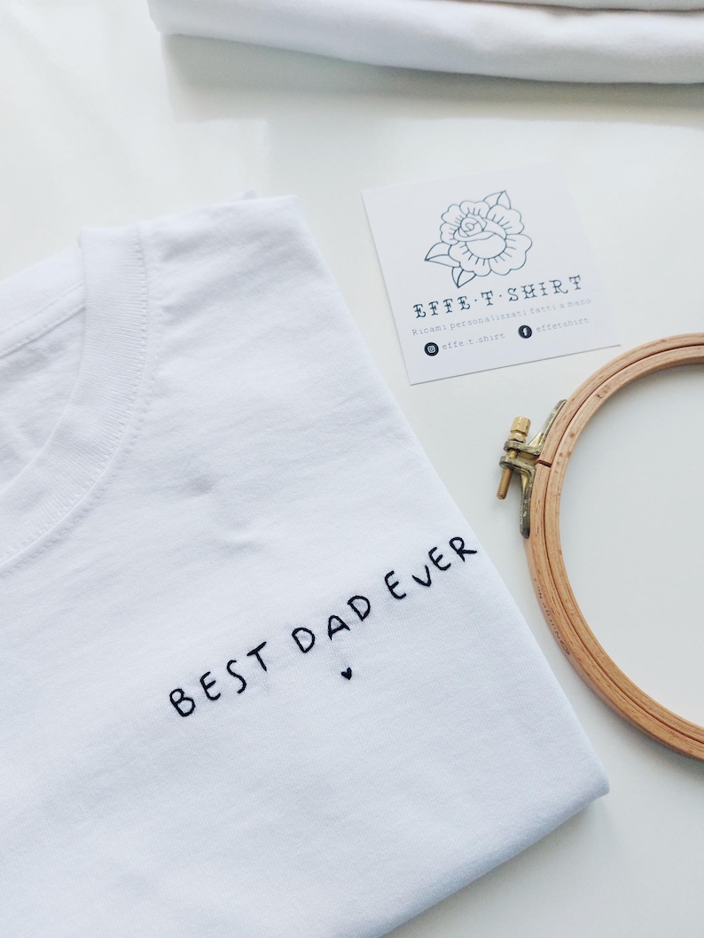 May include: White t-shirt with black embroidery that says "Best Dad Ever" with a small heart.