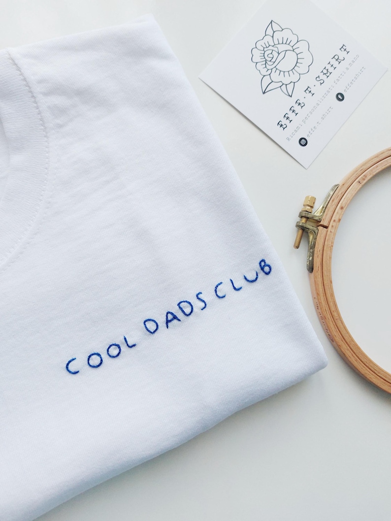 May include: White t-shirt with blue embroidery that reads "COOL DADS CLUB".