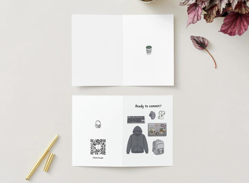 Peut inclure: Une carte de v&oelig;ux pli&eacute;e blanche avec une petite illustration de tasse de caf&eacute; &agrave; l'int&eacute;rieur. Le dos affiche un code QR, un casque et le texte Ready to commit? avec des illustrations de clavier, souris, sweat &agrave; capuche, ordinateur et sac &agrave; dos.