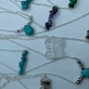 May include: A collection of silver necklaces with various gemstone pendants, including turquoise, amethyst and dalmatian jasper.
