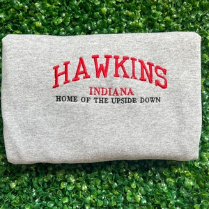 May include: Gray sweatshirt with red embroidered text that reads "Hawkins, Indiana, Home of the Upside Down".