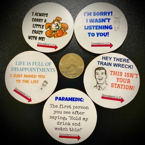 May include: Set of five round white coasters with black text and illustrations. The coasters feature humorous sayings such as "I always carry a little crazy with me!" and "Hey there train wreck! This isn't your station!"