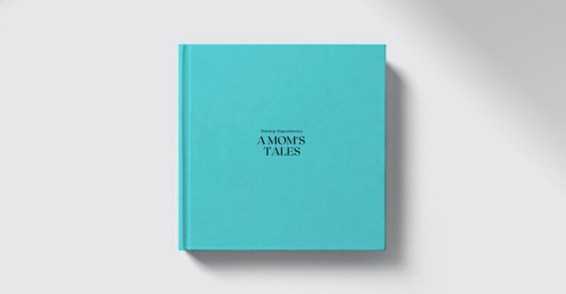 May include: A square, light blue book titled "A Mom's Tales" with the subtitle "Raising Superheroes" in black text. The book has a solid, textured cover and is centered on a white background. The book's spine is visible.