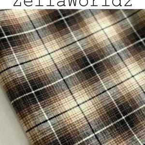Pu&ograve; includere: Un tessuto con un motivo a quadri marrone, nero e crema con un effetto sfumato. Il testo ZellaWorldz &egrave; stampato in nero nella parte superiore dell'immagine. Il materiale presenta una trama tessuta con linee orizzontali e verticali incrociate.