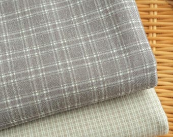 Può includere: Due pezzi di tessuto piegati impilati l'uno sull'altro. Il pezzo superiore è un tessuto grigio scuro con un motivo a griglia bianco. Il pezzo inferiore è un tessuto beige chiaro con un motivo a griglia bianco. Il testo ZellaWorldz è in alto.