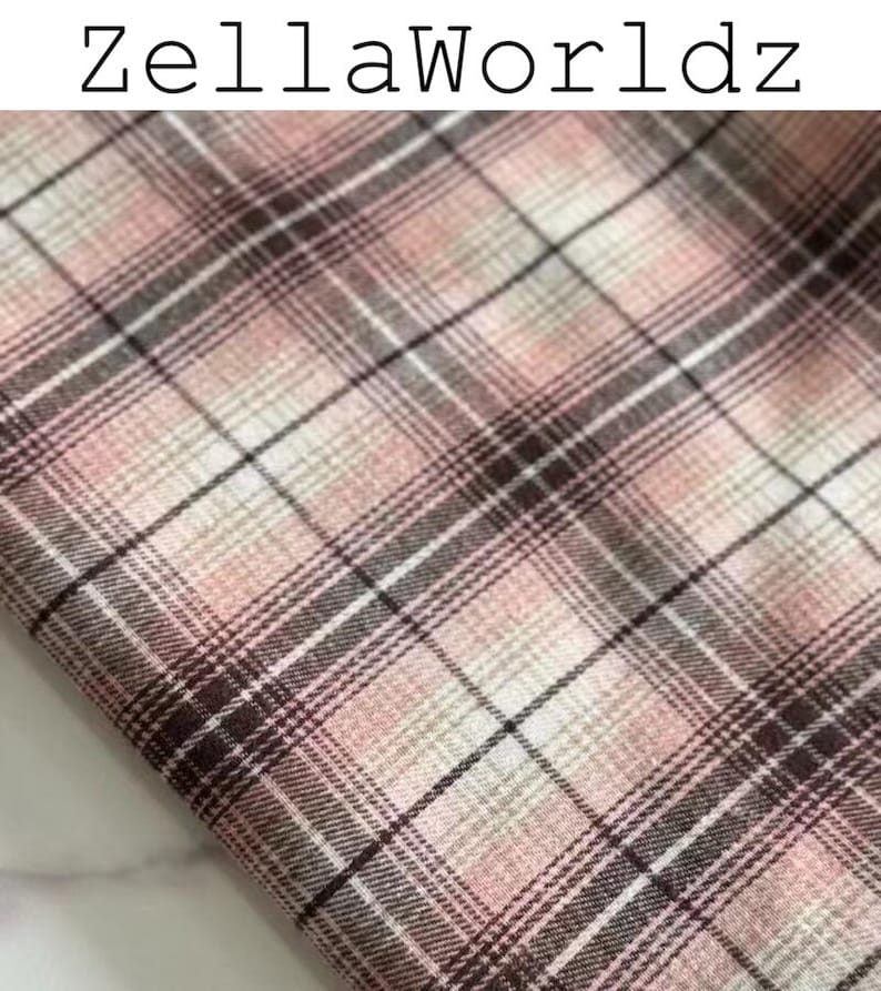 Pu&ograve; includere: Un campione di tessuto con un motivo a quadri nelle tonalit&agrave; rosa tenue, bianco e marrone scuro. Il tessuto presenta un design a griglia intrecciata con linee che si intersecano di vario spessore. Il testo ZellaWorldz &egrave; stampato in nero in alto.