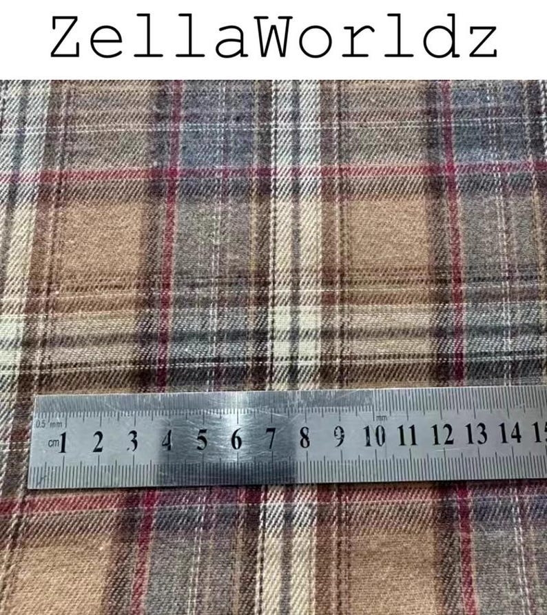 Pu&ograve; includere: Un tessuto intrecciato con un motivo a quadri nei toni del marrone chiaro, marrone, grigio e sottili linee rosse. Un righello in metallo &egrave; posizionato sul tessuto, mostrando una scala in centimetri da 1 a 15 cm. Il testo ZellaWorldz appare sopra.