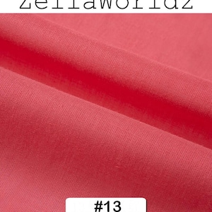 Peut inclure: Gros plan sur un morceau de tissu pli&eacute; de couleur corail. Le tissu a une texture douce et est l&eacute;g&egrave;rement froiss&eacute;. Le texte "ZellaWorldz" est en haut et le num&eacute;ro "#13" dans un rectangle blanc en bas.