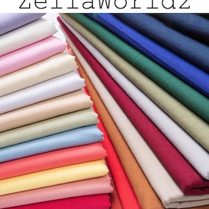 May include: A collection of folded fabric in a range of colours, such as pink, blue, green, and red. The text "ZellaWorldz" is visible at the top. The fabric is neatly stacked, suggesting it's ready for crafting or sewing projects.