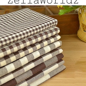 Może przedstawiać: Stos złożonych kwadratów z tkaniny w brązowo-kremową kratkę typu gingham. Kawałki materiału są starannie ułożone jeden na drugim, prezentując spójny wzór siatki na powierzchni każdego z poszczególnych kwadratów.
