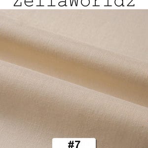 Peut inclure: Gros plan sur un tissu beige avec une texture et des plis visibles. Le texte "ZellaWorldz" est en haut et un rectangle blanc avec le num&eacute;ro "#7" est en bas.