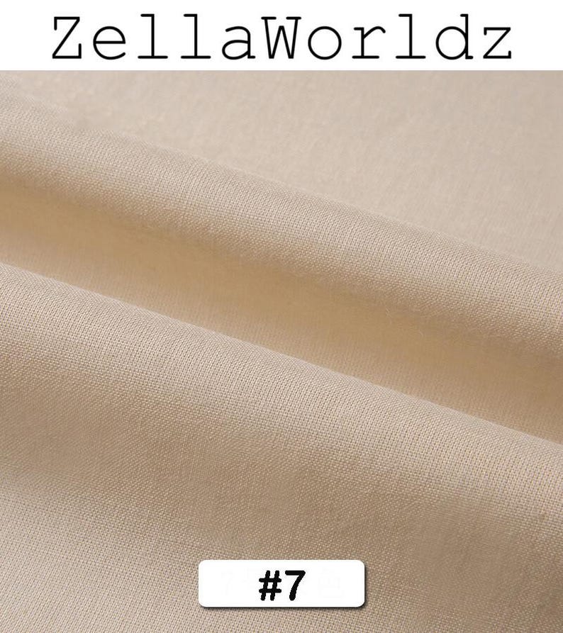 Peut inclure: Gros plan sur un tissu beige avec une texture et des plis visibles. Le texte "ZellaWorldz" est en haut et un rectangle blanc avec le num&eacute;ro "#7" est en bas.