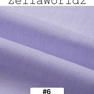Peut inclure: Gros plan sur un tissu violet clair avec une texture et des plis visibles. Le tissu est &eacute;tiquet&eacute; avec le texte "ZellaWorldz" en haut et le num&eacute;ro "#6" dans un rectangle blanc en bas. Le tissu semble &ecirc;tre une mati&egrave;re douce.