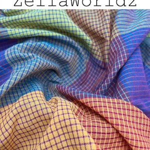 May include: A close-up of a colorful fabric with a checkered pattern. The fabric features a blend of blue, yellow, purple, and green hues. The text "ZellaWorldz" is displayed at the top of the image.