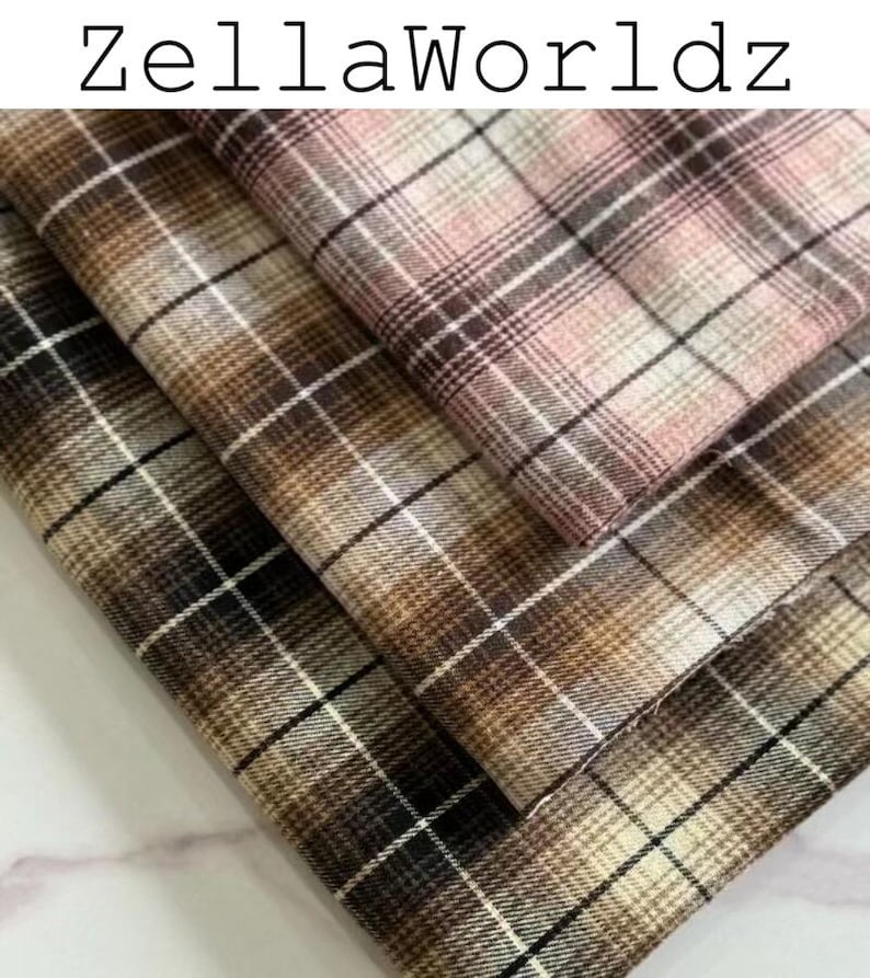 Pu&ograve; includere: Tre pezzi di tessuto piegati con un motivo a quadri e il testo ZellaWorldz in alto. Gli strati di tessuto mostrano una tavolozza di colori rosa tenue, varie tonalit&agrave; di marrone, beige e bianco, disposti in una griglia di linee incrociate.