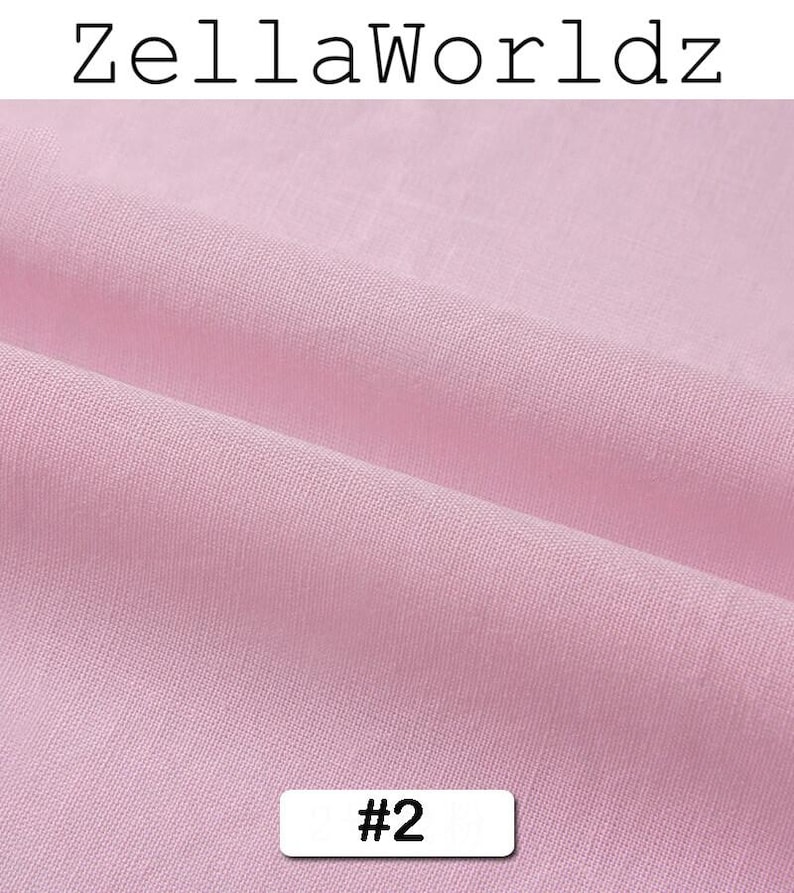 Peut inclure: Gros plan sur un tissu rose clair avec une texture visible et des plis. Le tissu porte le texte "ZellaWorldz" en haut et le num&eacute;ro "#2" dans un rectangle blanc en bas. Le tissu semble &ecirc;tre doux.