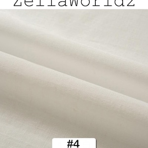 Peut inclure: Gros plan sur un tissu blanc cass&eacute; avec une texture et des plis visibles. Le texte "ZellaWorldz" est en haut et un rectangle blanc avec le num&eacute;ro "#4" est en bas.