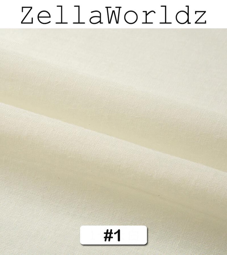 Peut inclure: Gros plan sur un tissu cr&egrave;me avec une texture visible et des plis. Le texte "ZellaWorldz" est en haut, et une &eacute;tiquette avec le num&eacute;ro "#1" est en bas. Le tissu semble &ecirc;tre une mati&egrave;re naturelle.