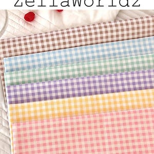 May include: A stack of gingham fabric in various pastel colors, including pink, yellow, purple, green, and blue. The fabric is arranged in a layered pattern, with the text "ZellaWorldz" at the top.
