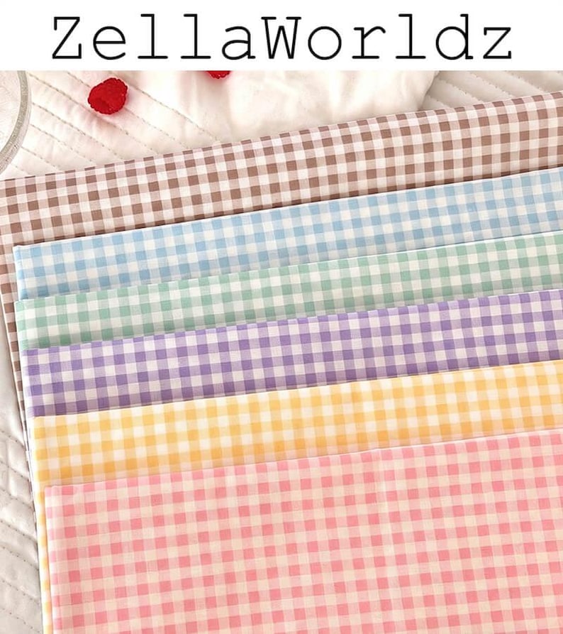 May include: A stack of gingham fabric in various pastel colors, including pink, yellow, purple, green, and blue. The fabric is arranged in a layered pattern, with the text "ZellaWorldz" at the top.