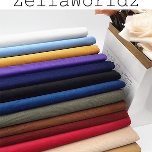May include: A stack of 15 different colored corduroy fabric swatches. The swatches are arranged in a rainbow pattern, starting with white and ending with black. The fabric is a soft, textured material that is perfect for clothing, home decor, and crafts.