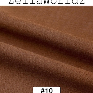 Peut inclure: Gros plan sur un tissu marron avec une texture et des plis visibles. Le tissu est d'une teinte chaude et terreuse. Le texte "ZellaWorldz" est en haut et une &eacute;tiquette avec "#10" est en bas.