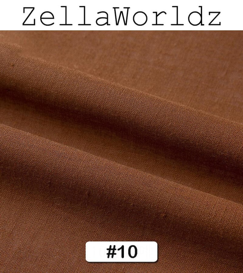 Peut inclure: Gros plan sur un tissu marron avec une texture et des plis visibles. Le tissu est d'une teinte chaude et terreuse. Le texte "ZellaWorldz" est en haut et une &eacute;tiquette avec "#10" est en bas.