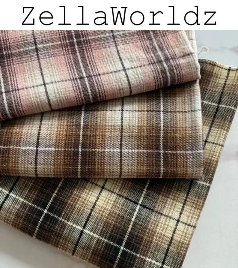 Pu&ograve; includere: Tre pezzi di tessuto piegati con un motivo a quadri e il testo ZellaWorldz in alto. Il tessuto superiore &egrave; rosa e marrone, quello centrale &egrave; marrone e beige, e quello inferiore &egrave; marrone scuro, beige e nero con una griglia di sottili linee bianche.