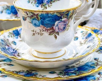 May include: A white teacup and saucer set with a blue and pink floral pattern. The set has a gold trim around the edges.