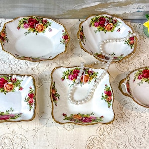 May include: Five vintage porcelain bowls with a floral design and gold trim. The bowls are in various shapes and sizes, and one has handles.