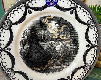 May include: A black and white ceramic plate with a Halloween scene featuring a witch, a cat, and a pumpkin. The plate has a black and white border with a scalloped edge. The plate is made by Royal Stafford and says "Made in England" on the back.