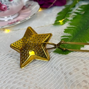 May include: Gold star-shaped tea infuser with a long handle. The infuser has a fine mesh design and is perfect for steeping loose leaf tea.